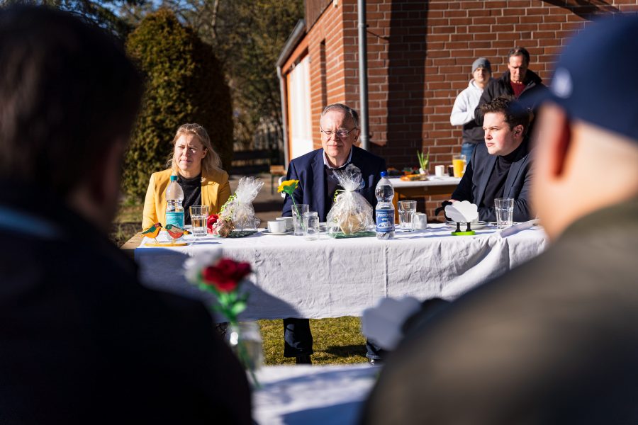 Kirsikka Lansmann, Stephan Weil und Philipp Ralfs sitzen im Garten der Dachstiftung Diakonie und tauschen sich mit den Menschen aus